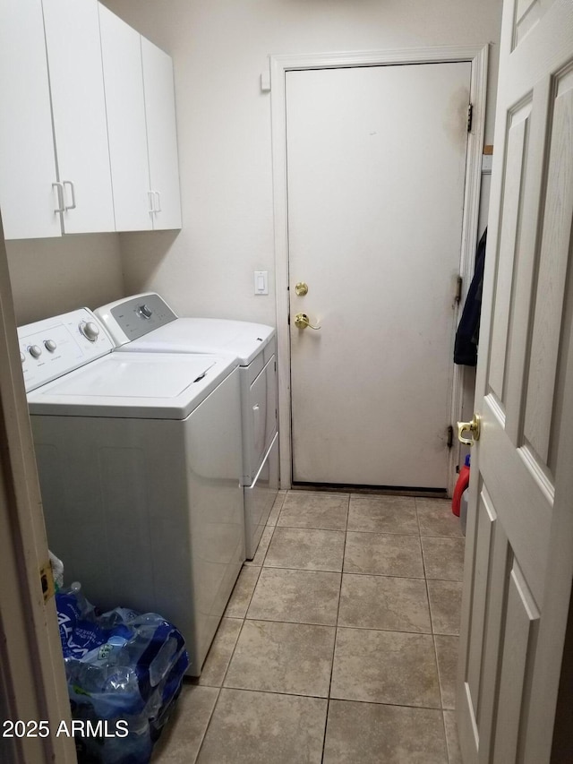 laundry room with light tile patterned flooring, washing machine and clothes dryer, and cabinets