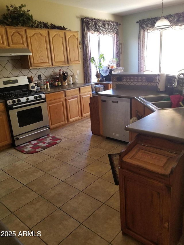 kitchen with gas range, hanging light fixtures, dishwashing machine, light tile patterned flooring, and sink