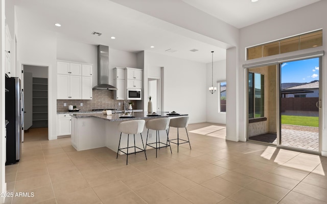 27908 N 38th Dr, Phoenix, AZ 85083 - kitchen with a kitchen island with sink, built in microwave, visible vents, backsplash, and wall chimney range hood