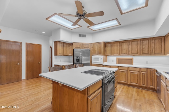 8604 S Oak St, Tempe, AZ 85284 - kitchen featuring appliances with stainless steel finishes, a kitchen island, brown cabinetry, and light wood-type flooring
