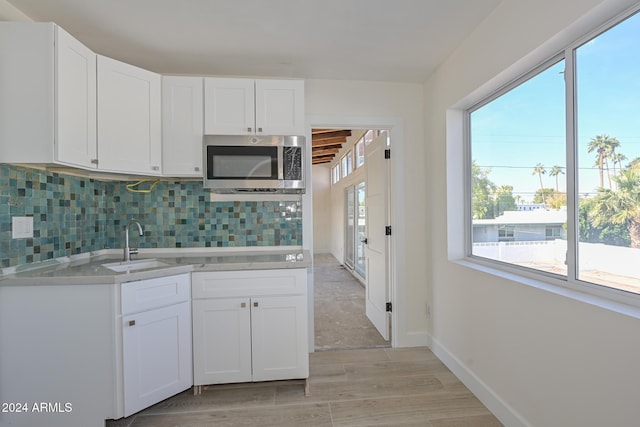 6312 N 13th St, Phoenix, AZ 85014 - kitchen featuring stainless steel microwave, a sink, tasteful backsplash, light countertops, and white cabinets