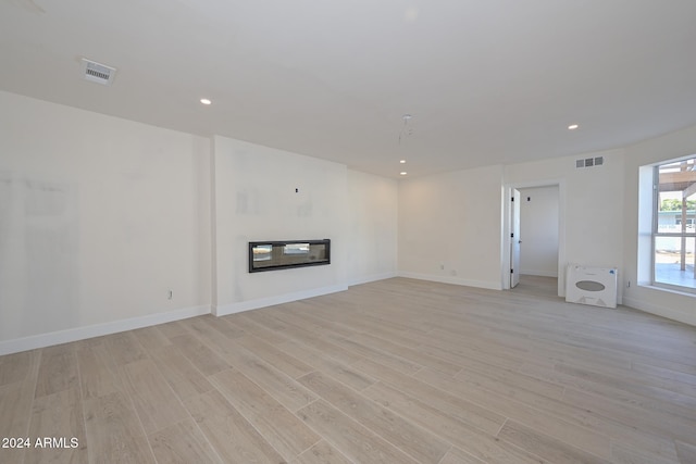 6312 N 13th St, Phoenix, AZ 85014 - unfurnished living room with light wood-type flooring, a glass covered fireplace, recessed lighting, and baseboards