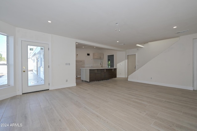 6312 N 13th St, Phoenix, AZ 85014 - unfurnished living room with light wood-style flooring, a sink, baseboards, and recessed lighting