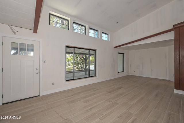6312 N 13th St, Phoenix, AZ 85014 - unfurnished living room featuring light wood-style floors, a towering ceiling, and baseboards
