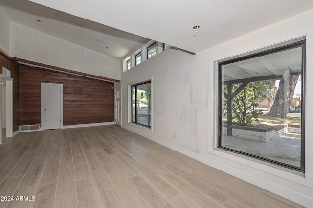 6312 N 13th St, Phoenix, AZ 85014 - unfurnished living room with light wood-style flooring, a towering ceiling, and baseboards