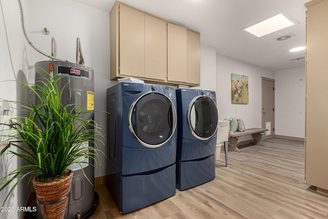 clothes washing area featuring cabinets, electric water heater, light hardwood / wood-style flooring, and washing machine and dryer