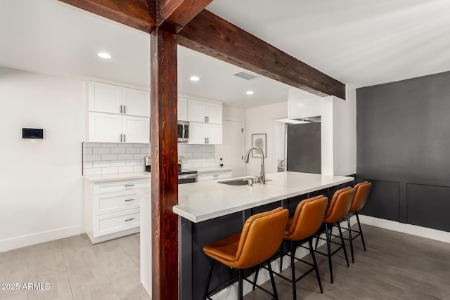 3038 E Avalon Dr, Phoenix, AZ 85016 - kitchen featuring a sink, appliances with stainless steel finishes, backsplash, a breakfast bar area, and light countertops