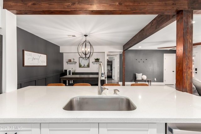 3038 E Avalon Dr, Phoenix, AZ 85016 - kitchen featuring a sink, open floor plan, beamed ceiling, a chandelier, and light stone counters