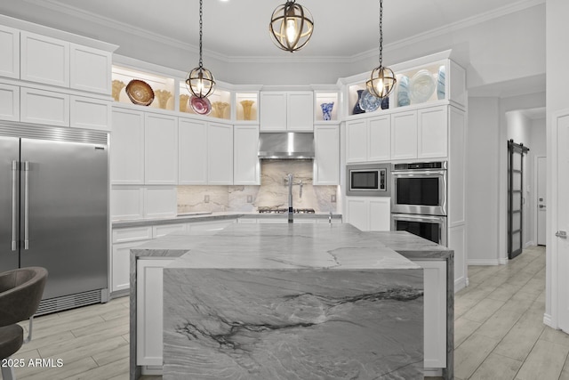 kitchen with extractor fan, light stone countertops, pendant lighting, and built in appliances