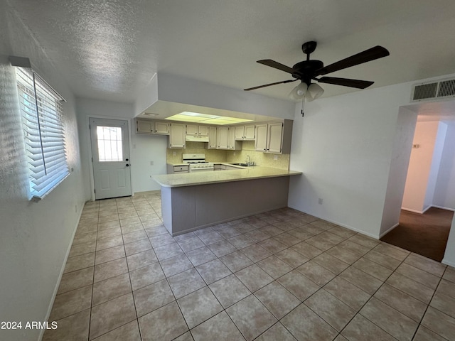 kitchen featuring ceiling fan, kitchen peninsula, white range oven, light tile flooring, and sink