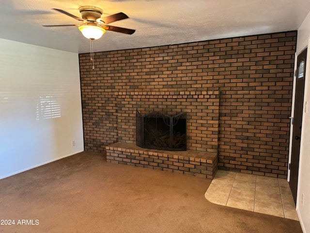 unfurnished living room featuring brick wall, carpet floors, a brick fireplace, and ceiling fan