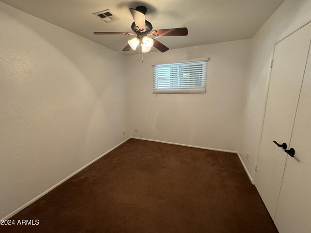 unfurnished bedroom with a closet, ceiling fan, and dark carpet