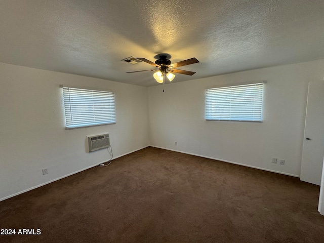 carpeted empty room with a wall unit AC, ceiling fan, a healthy amount of sunlight, and a textured ceiling