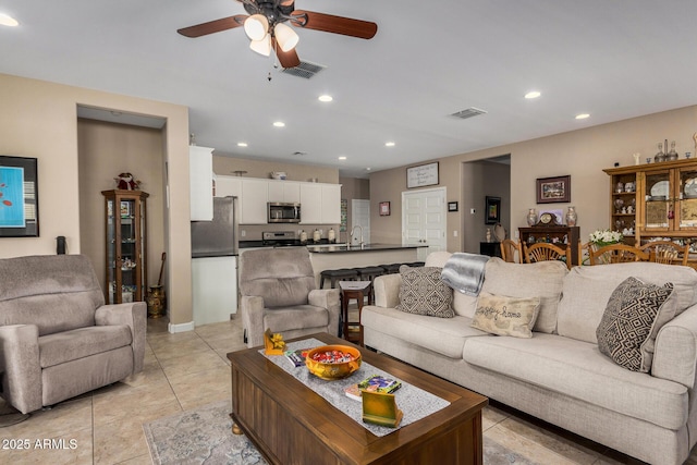 tiled living room with ceiling fan and sink