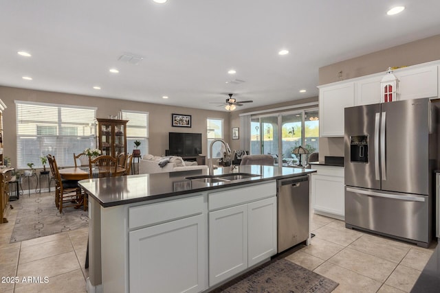 kitchen with white cabinetry, stainless steel appliances, a kitchen island with sink, light tile patterned flooring, and sink