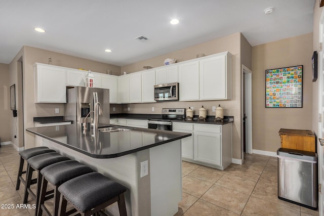 kitchen featuring white cabinets, appliances with stainless steel finishes, sink, and a breakfast bar area