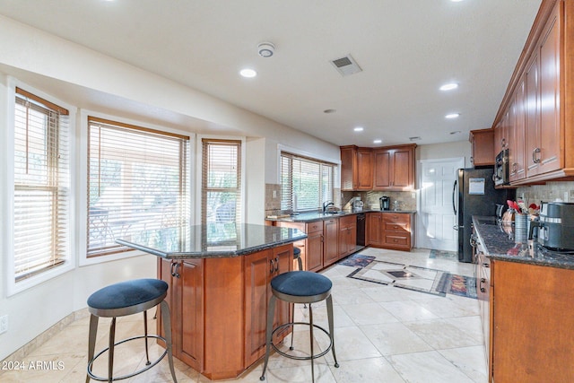 kitchen with dark stone countertops, decorative backsplash, and a breakfast bar area