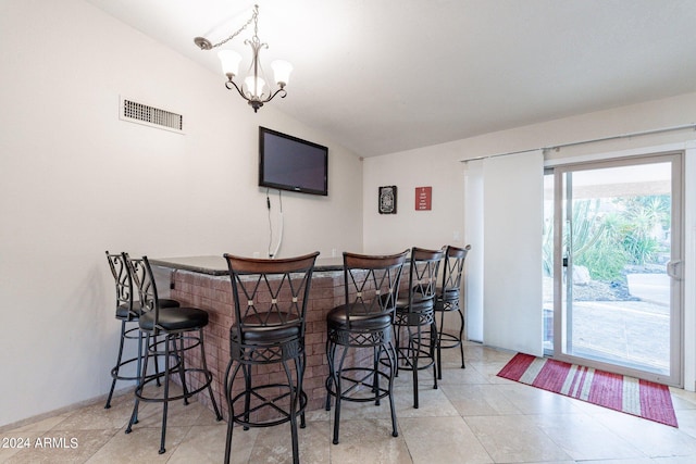 bar with a notable chandelier, vaulted ceiling, and light tile patterned floors