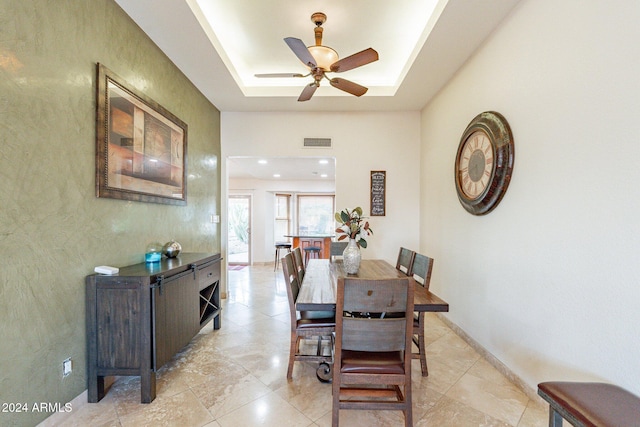 dining area with ceiling fan and a tray ceiling