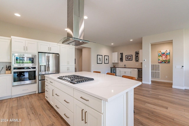 kitchen with island exhaust hood, appliances with stainless steel finishes, light wood-type flooring, and white cabinetry