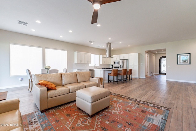 living room with sink, light hardwood / wood-style floors, and ceiling fan