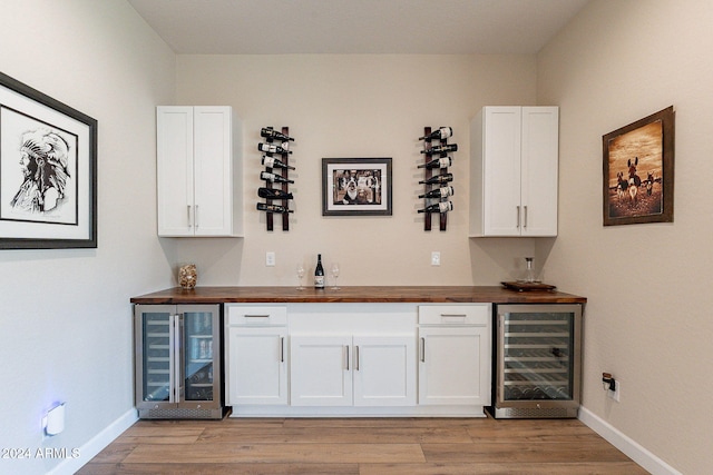 bar featuring butcher block counters, light hardwood / wood-style floors, and beverage cooler