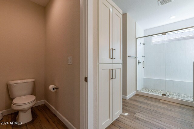 bathroom with a shower with shower door, hardwood / wood-style flooring, and toilet