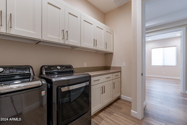 washroom featuring cabinets, light hardwood / wood-style flooring, and washing machine and clothes dryer