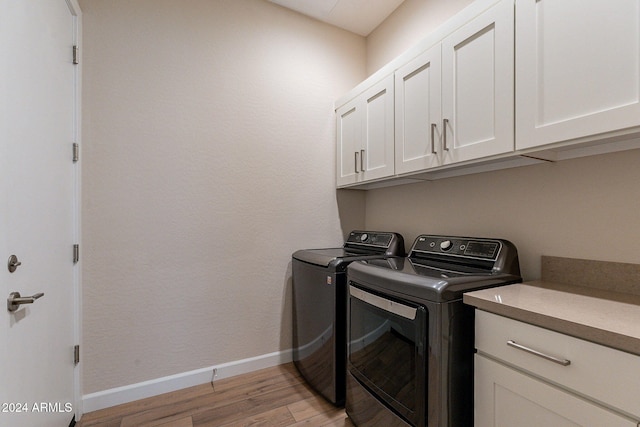 clothes washing area with washing machine and dryer, cabinets, and light wood-type flooring