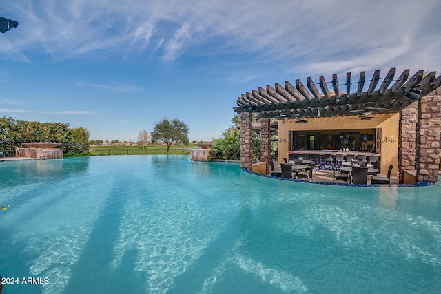 view of pool with pool water feature, a water view, and a pergola