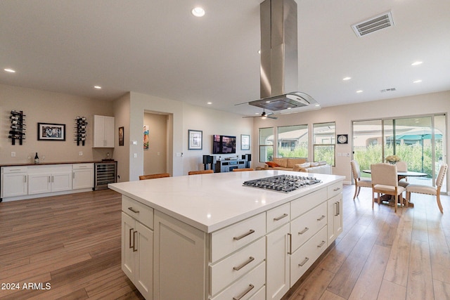 kitchen featuring island range hood, a kitchen island, wine cooler, stainless steel gas stovetop, and light hardwood / wood-style floors