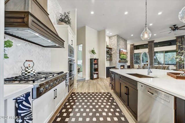 kitchen featuring pendant lighting, custom exhaust hood, sink, appliances with stainless steel finishes, and white cabinetry