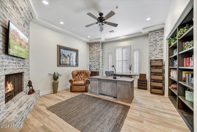 office space with a large fireplace, ceiling fan, and light hardwood / wood-style floors