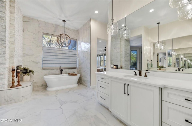 bathroom featuring vanity, a bath, ceiling fan with notable chandelier, and tile walls