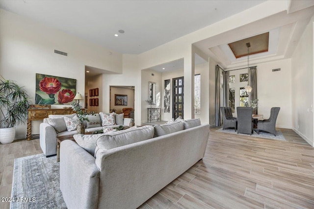 living room with light hardwood / wood-style floors and a tray ceiling