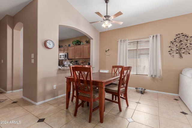 dining space with ceiling fan, sink, vaulted ceiling, and light tile patterned floors