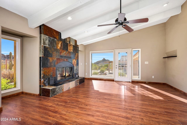 unfurnished living room with lofted ceiling with beams, ceiling fan, a fireplace, and wood-type flooring