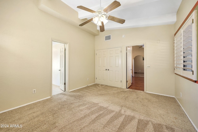 unfurnished bedroom featuring vaulted ceiling with beams, ceiling fan, light colored carpet, and a closet