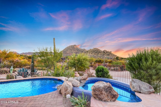 pool at dusk featuring a mountain view and a patio area