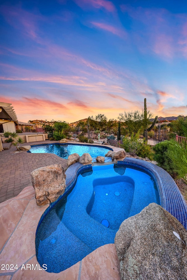 pool at dusk with a patio area