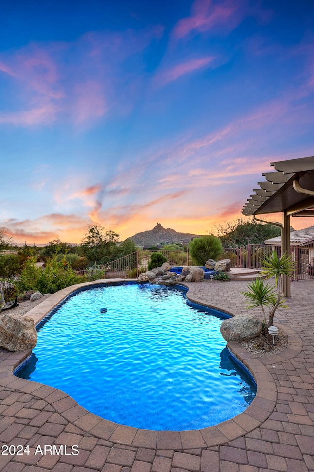 pool at dusk featuring a patio area