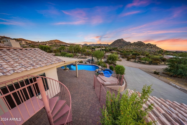 pool at dusk featuring a mountain view and a patio area