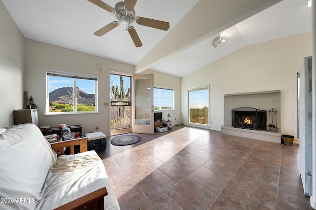 living room featuring ceiling fan, a brick fireplace, lofted ceiling with beams, tile patterned floors, and a mountain view