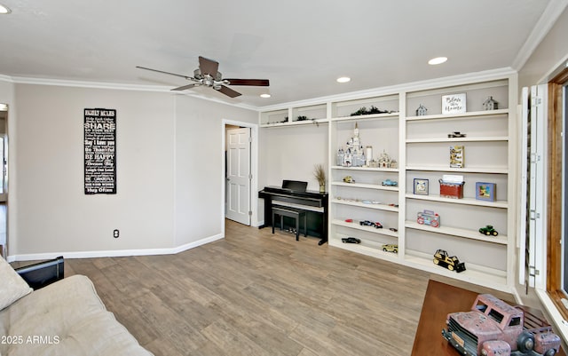 living area with wood-type flooring, ornamental molding, and ceiling fan