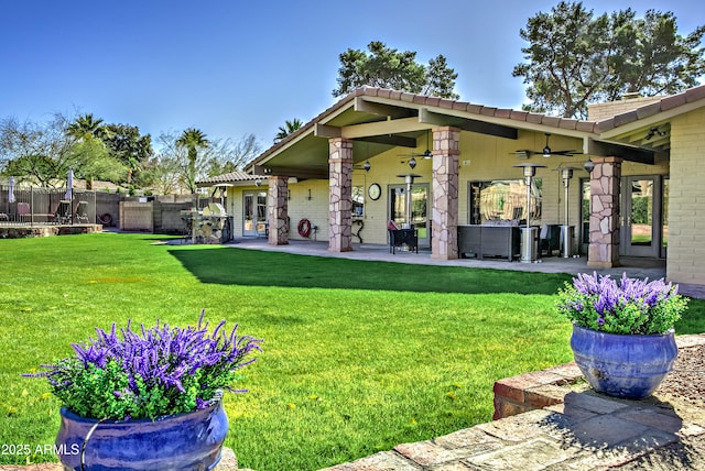 back of property with a yard, ceiling fan, and a patio area