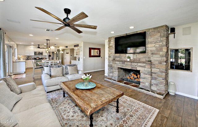 living room with ceiling fan, a fireplace, and light hardwood / wood-style flooring