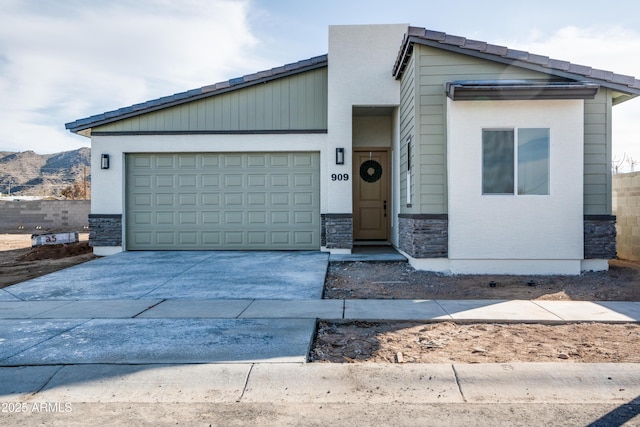 view of front of house with a mountain view, stone siding, an attached garage, and driveway