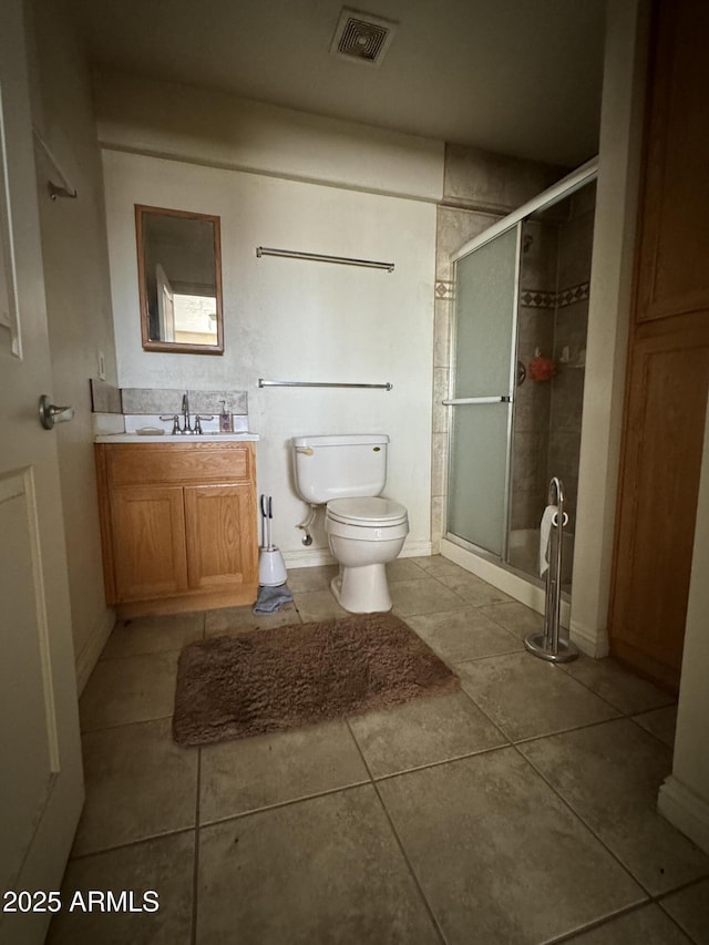 bathroom with vanity, a shower with shower door, tile patterned floors, and toilet