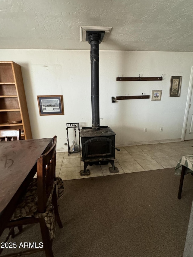 living room featuring a wood stove, light tile patterned floors, and a textured ceiling