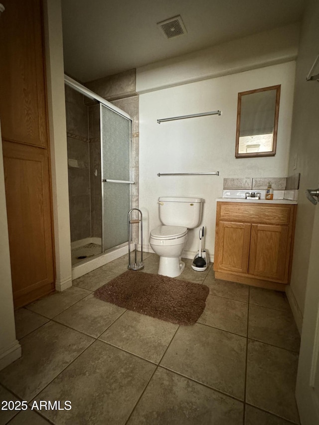 bathroom featuring tile patterned flooring, vanity, a shower with shower door, and toilet